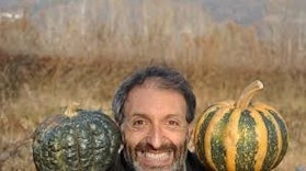 Signore con barba scura con la faccia tra due zucche