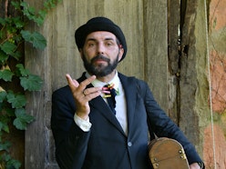 Bombetta Book | Relatori della Tre Giorni per il Giardino © FAI Ragazzo con barba scura che indossa una bombetta nera e una giacca con camicia bianca. In mano tiene un bauletto di legno